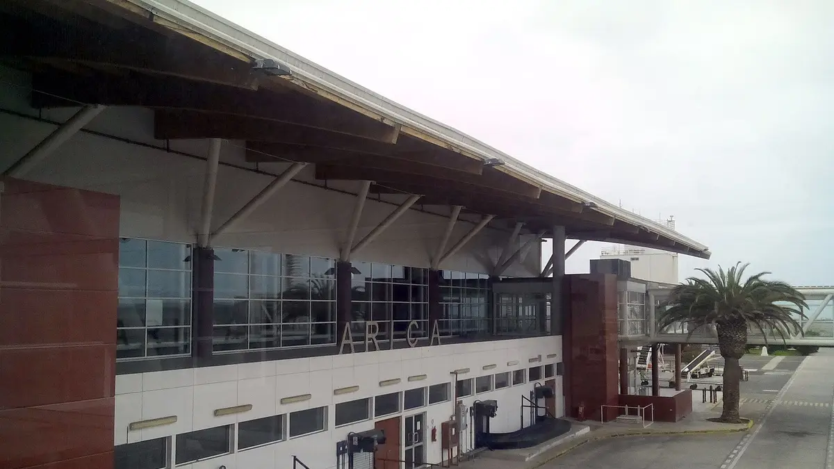 Terminal del aeropuerto Chacalluta de Arica con techo metálico y palmeras