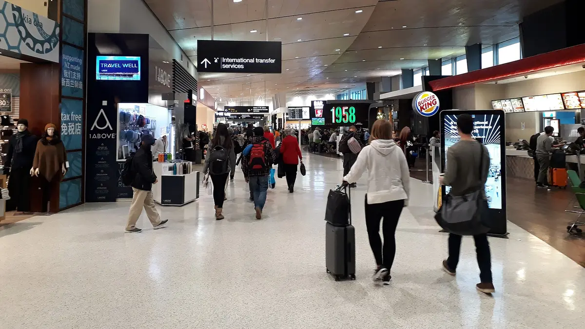 Pasillo interior del aeropuerto de Santiago con pasajeros caminando hacia las puertas de embarque