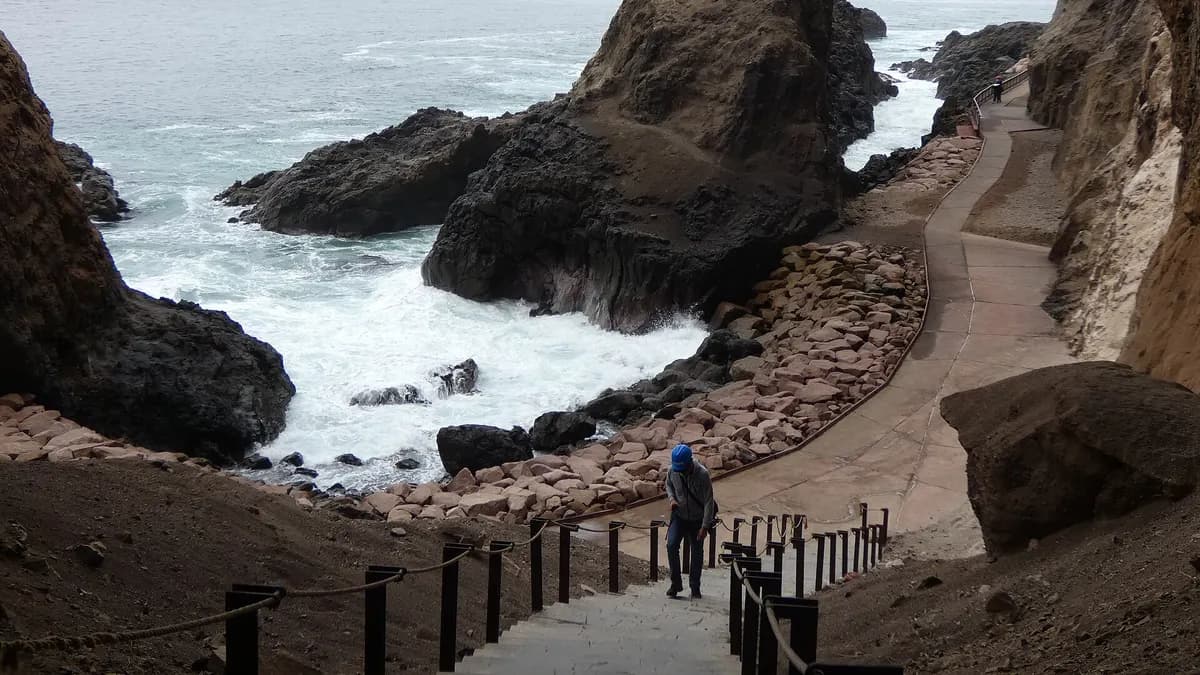 Pasarela con barandas entre roqueríos y oleaje en el sendero de Anzota