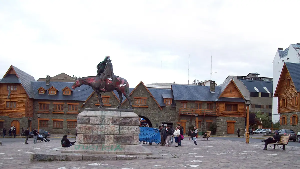 Centro Cívico de Bariloche con edificios de piedra y madera y una estatua ecuestre al centro de la plaza