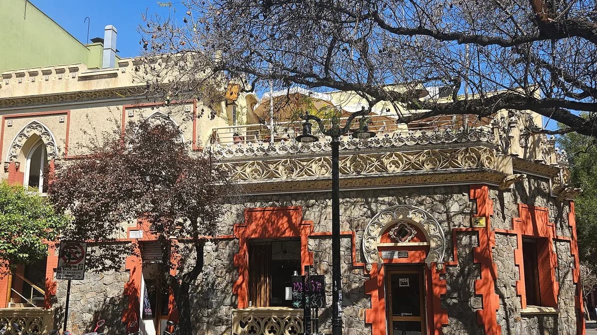 Fachada roja de un edificio antiguo entre árboles en una calle de Lastarria