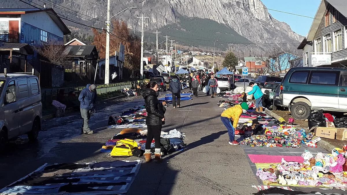 Toldos y puestos de feria en una calle de Coyhaique, con montañas detrás