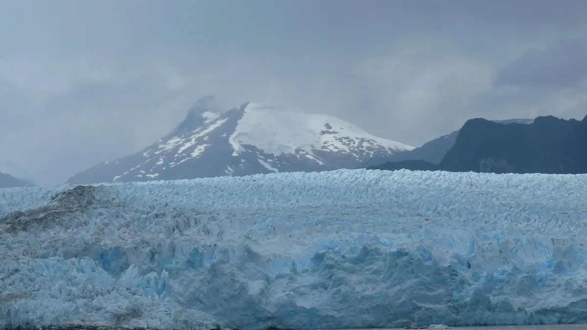 Muro de hielo azulado del Pío XI con una cumbre nevada al fondo