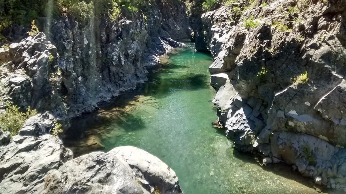 Pozas verdes encadenadas entre paredes oscuras de basalto en el río Claro