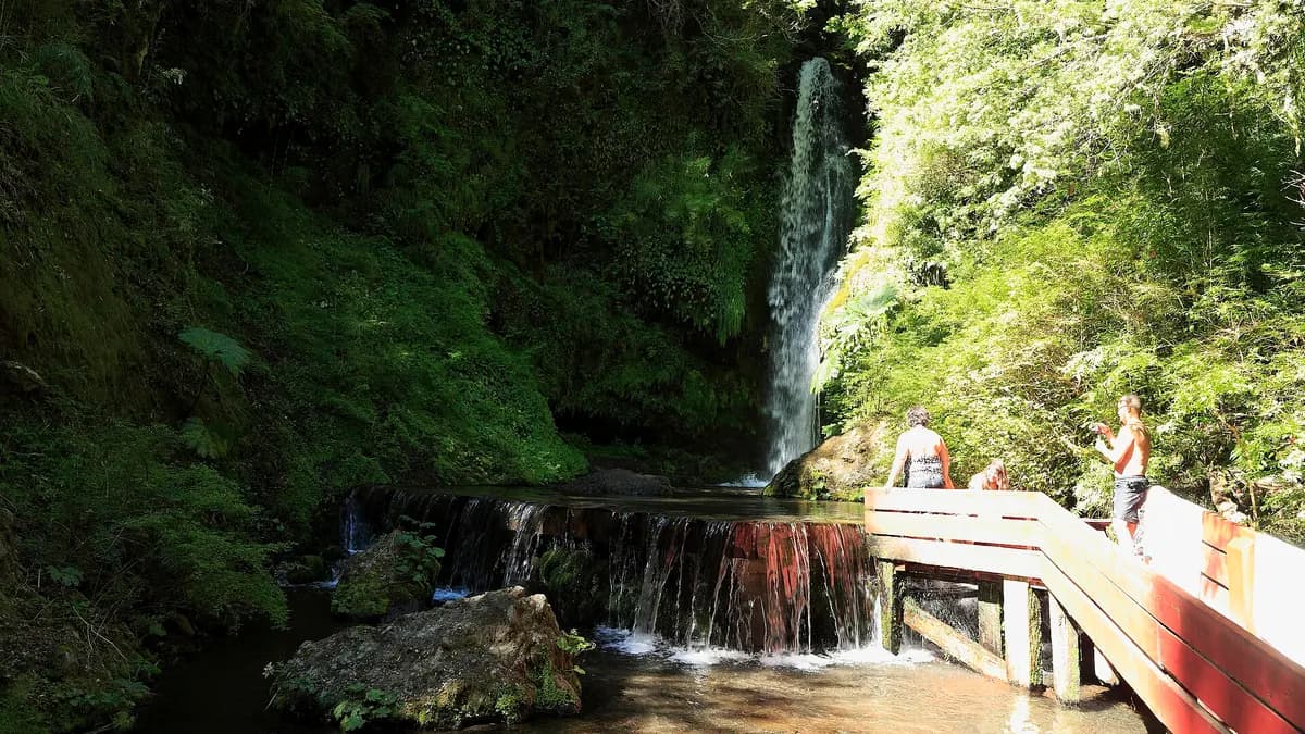 Chorro de agua fría cayendo a una poza de piedra al lado de la pasarela roja