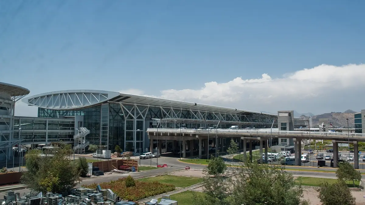 Fachada del terminal de pasajeros del aeropuerto de Santiago con estacionamientos y jardines al frente
